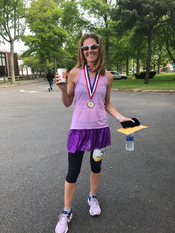 Dr. Gelnett smiling with a finisher&rsquo;s medal after a road race